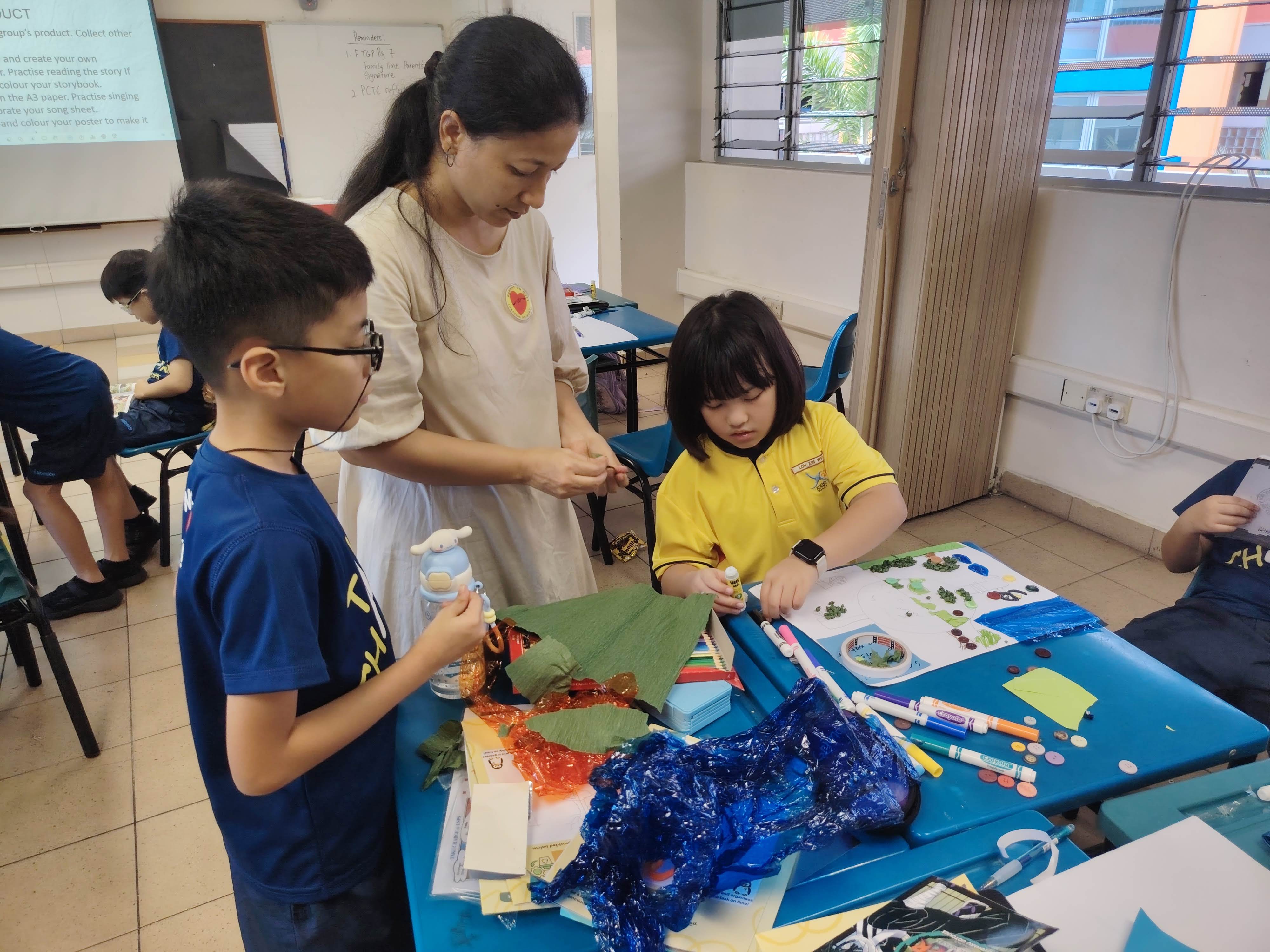 Two students with a parent volunteer working together to create the prototype in class for their presentation